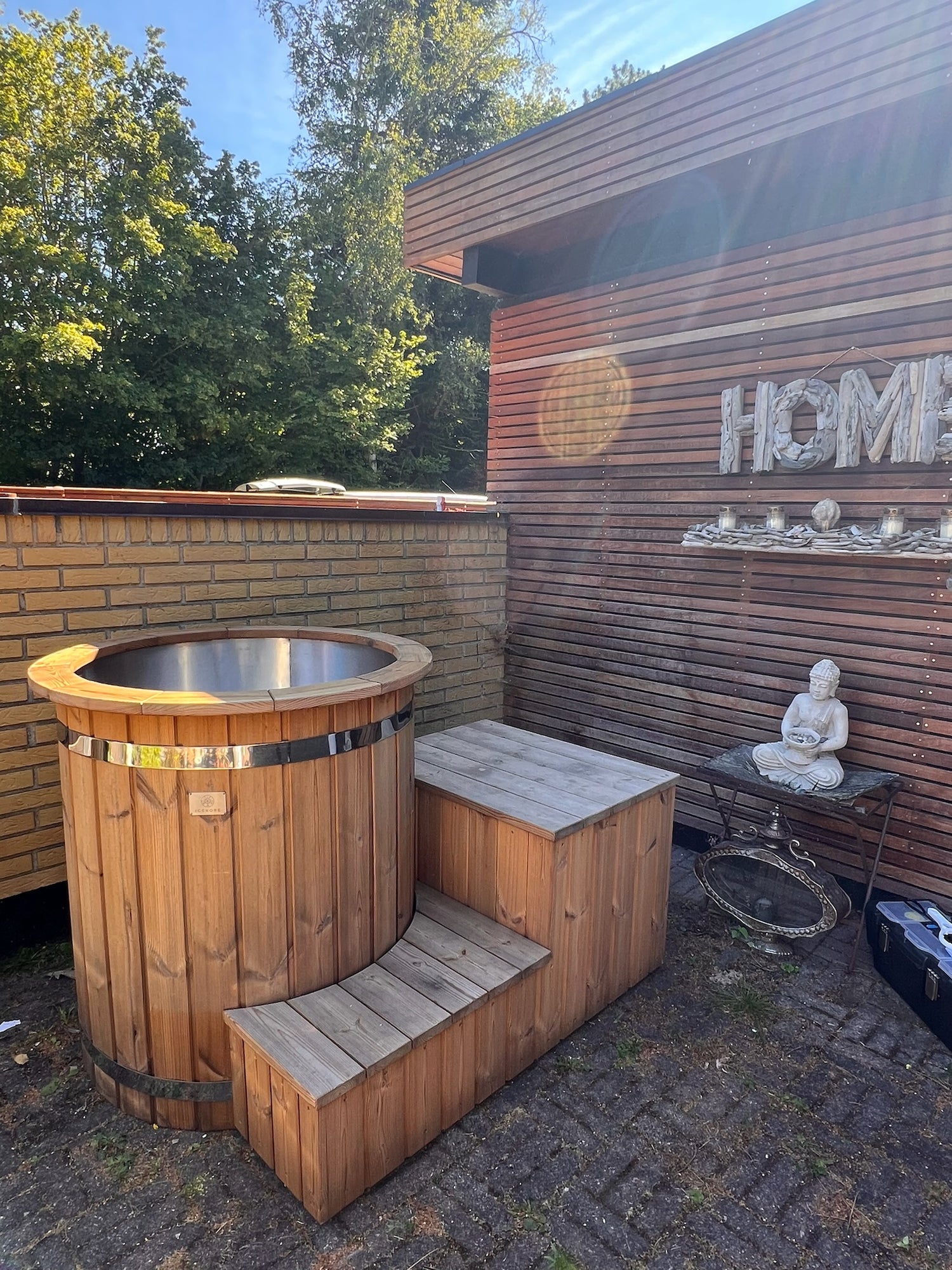 Isbad i træ med metalindsats, trappe og Buddha-statue udendørs