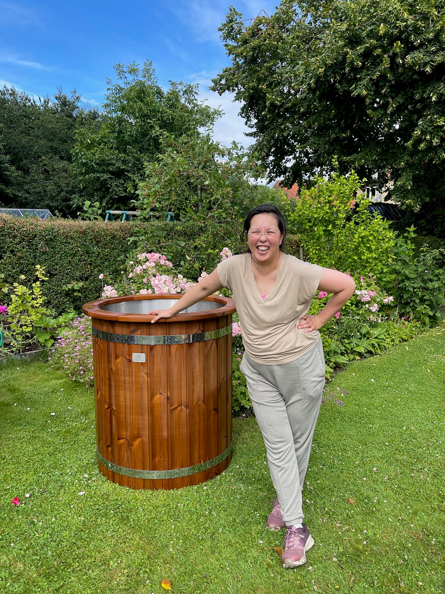 Kvinde smiler ved siden af en isbalje i træ i haven